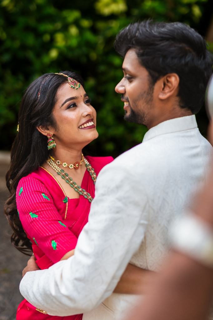 Pre-Wedding — Bride smiling as groom holds her close, garden backdrop