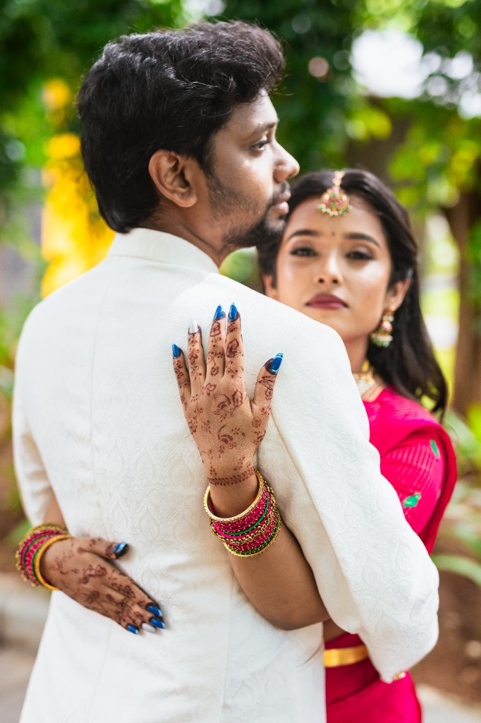 Pre-Wedding — Bride with mehndi hands holding groom from behind, garden