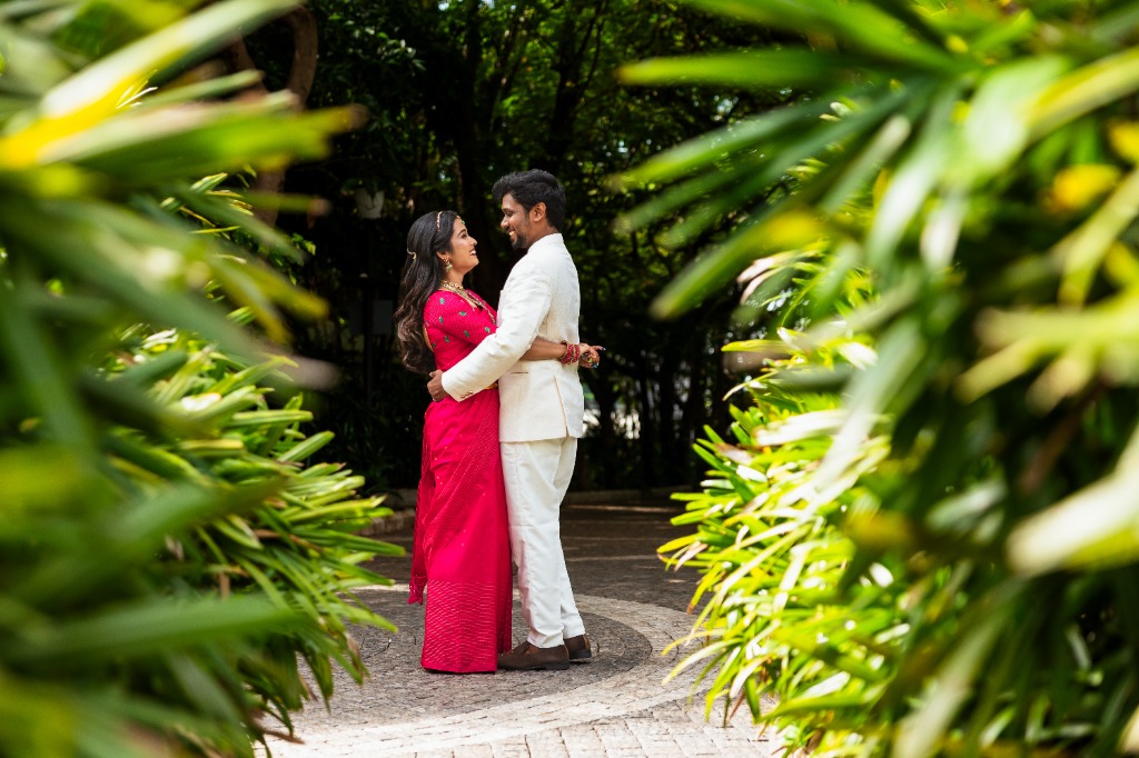 Pre-Wedding — Couple embracing in garden, framed by leaves