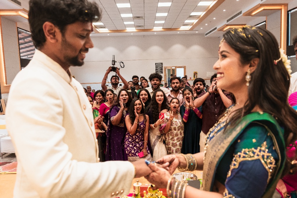 Engagement — Crowd cheering at ring ceremony, Karthik placing ring