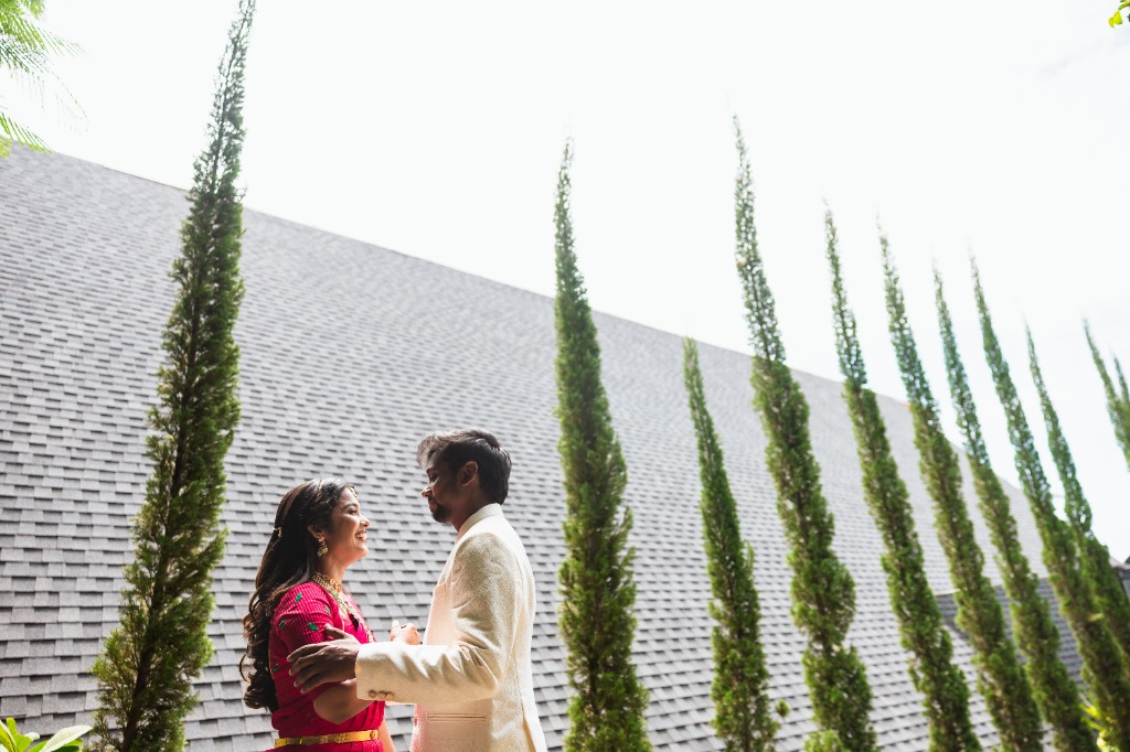 Pre-Wedding — Couple face-to-face beside tall cypress trees