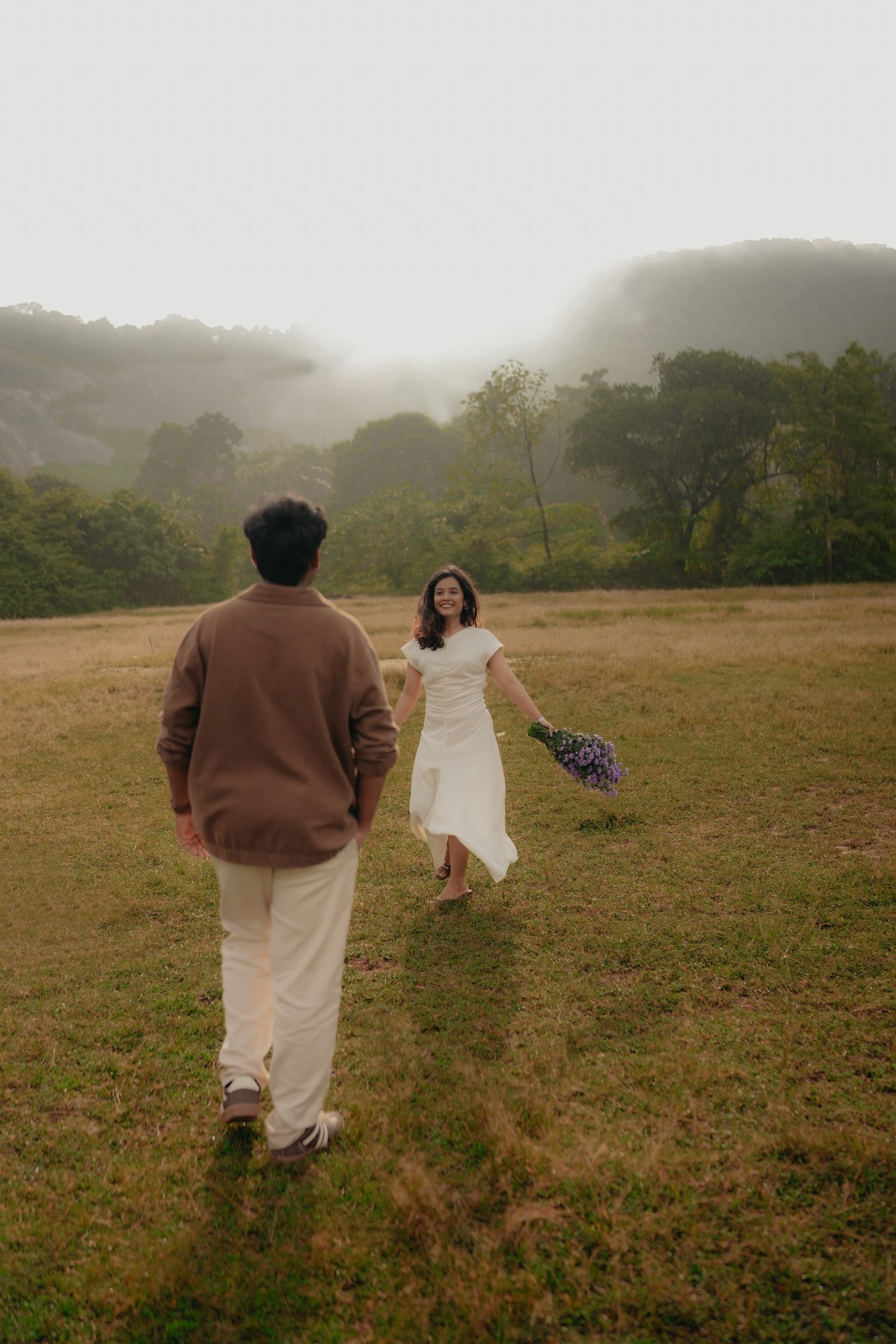 Pre-Wedding — Mirunalini & Karthik running together in foggy green meadow