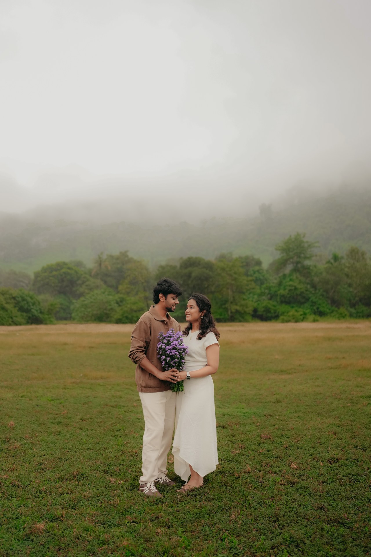Pre-Wedding — Karthik & Mirunalini laughing while running in meadow with bouquet
